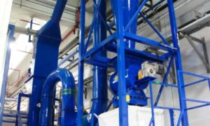 Separatore aeraulico zig zag industriale blu di Ghirarduzzi SRL, utilizzato per la separazione di materiali in impianti di riciclo e recupero, installato all'interno di un ambiente industriale, ideale per processi di separazione di materiali con diversa densità e peso specifico