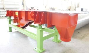 Industrial vibrating feeder by Ghirarduzzi in red and green, designed for high-precision material flow in manufacturing applications.